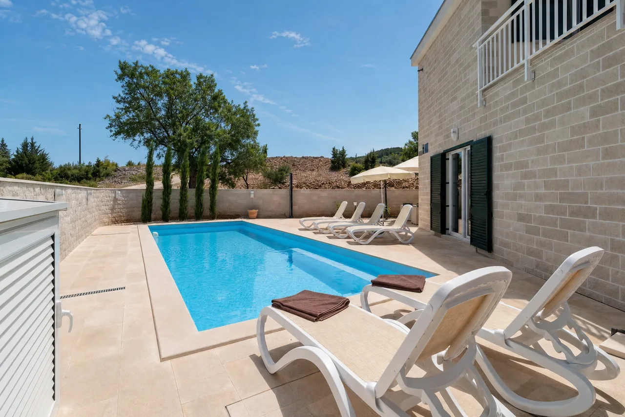 Pool with loungers next to a stone house